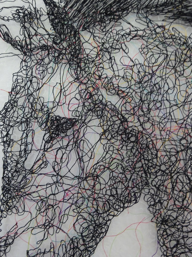May include: A black and white abstract art piece made of thread. The thread is woven together to create a design that resembles a face.