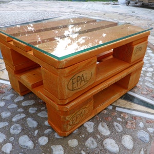Può includere: Un tavolino da caffè in legno realizzato con pallet riutilizzati con un piano in vetro. Il tavolo è tinto di arancione e ha il testo "EPAL" stampato sui lati.