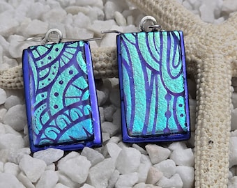 May include: A pair of blue and green rectangular earrings with a silver hook. The earrings have a geometric pattern and a blue border.
