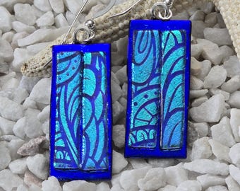 May include: A pair of blue and turquoise glass earrings with a silver hook. The glass is textured with a swirling pattern.