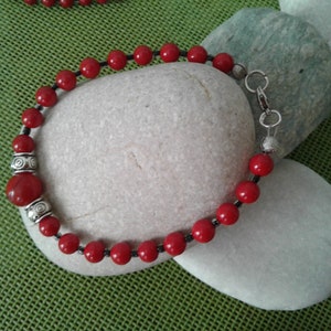 Puede incluir: Pulsera de cuentas rojas con detalles plateados y cierre de langosta.