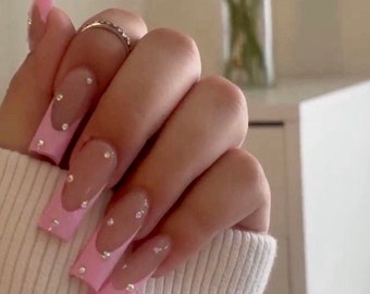 May include: Pink and clear long square-shaped nails with rhinestones on each nail.