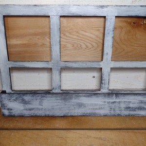 May include: A whitewashed wooden picture frame with six rectangular openings. The frame has a distressed look with a black base.