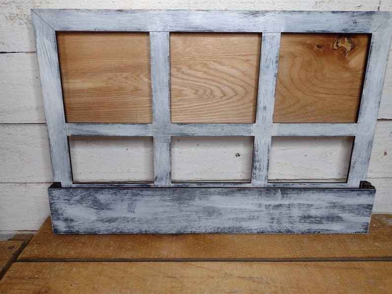 K&ouml;nnte beinhalten: Ein wei&szlig; gestrichener Holzrahmen mit sechs rechteckigen &Ouml;ffnungen. Der Rahmen hat einen abgenutzten Look mit einer schwarzen Basis.