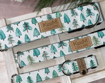 May include: Three dog collars with a white background and a green watercolor pattern of pine trees. The collars have silver hardware and a brown leather tag that says "KandM Collars".
