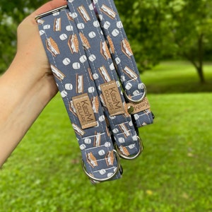 May include: Two dog collars with a blue background and a pattern of brown graham crackers and white marshmallows. The collars are made by K and M Collars.