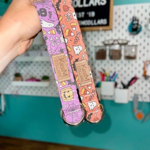May include: Two Halloween-themed dog collars, one orange and one purple, with a ghost, pumpkin, and candy corn pattern. The collars are made by K and M Collars.