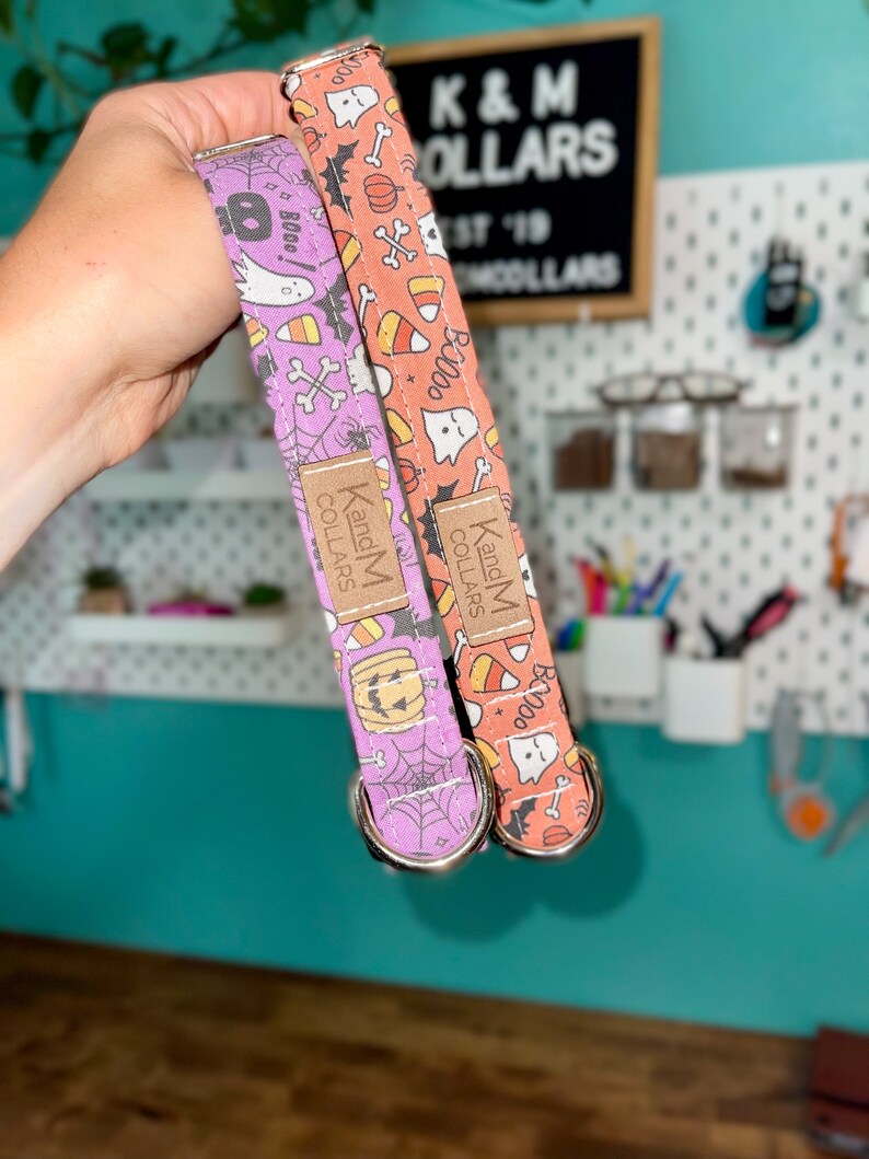 May include: Two Halloween-themed dog collars, one orange and one purple, with a ghost, pumpkin, and candy corn pattern. The collars are made by K and M Collars.