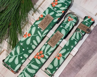 May include: Three green dog collars with a white and red holly berry pattern. The collars have silver hardware and a brown leather tag that says "Kang'M Collars".