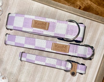Puede incluir: Tres collares de perro a cuadros morados y blancos con herrajes plateados y una etiqueta de cuero marrón que dice "K and M Collars".