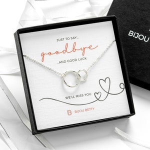 May include: A silver necklace with two interlocking circles, packaged in a black box with the text "JUST TO SAY goodbye AND GOOD LUCK" and "WE'LL MISS YOU" on the front. The box also features the logo "B BIJOU BETTY".