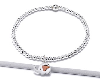 Puede incluir: Un brazalete de plata con cuentas y un pequeño dije de elefante de plata con un acento de oro rosa.
