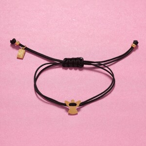 Close-up of 13mm stainless steel angel on black cord bracelet, perfect for sympathy or birthday gifts.
