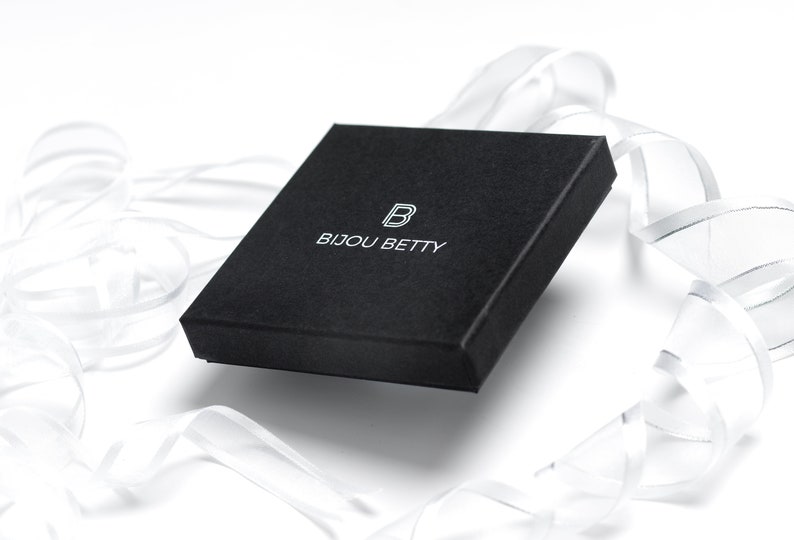 May include: A black square box with the text "Bijou Betty" and a stylized "B" logo printed in white.