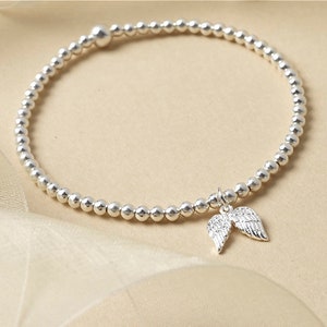 May include: A silver beaded bracelet with a small silver angel wing charm.