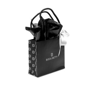 May include: A small black gift bag with the text "BIJOU BETTY" in white. The bag has a textured surface and a repeating pattern of the letter "B". Black tissue paper and a white ribbon peek out from the top.