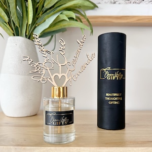 May include: A clear glass diffuser bottle with a gold lid and a wooden topper with the names "Amanda", "Cassandra", "Love", "Sophia", and "Josephine" engraved on it. The bottle has a label that says "Chain Valley Gifts". The diffuser bottle is packaged in a black tube with gold lettering that says "Chain Valley Gifts" and "Beautifully Thoughtful Gifting".