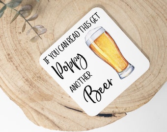 May include: White square coaster with black text that reads "If you can read this get another beer". A cartoon illustration of a glass of beer with a white head is on the coaster.