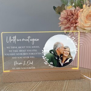 May include: A white acrylic light-up sign with a photo of an older couple. The sign reads "Until we meet again" and includes the text "We think about you always, we talk about you still, you have never been forgotten, and you never will. Mum & Dad. We miss you forever."