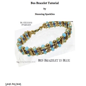 May include: A tutorial for a Bes bracelet in blue. The bracelet features light blue and dark blue beads with gold-colored metal accents. The text "Bes Bracelet Tutorial" and "Bes Bracelet in Blue" are visible.