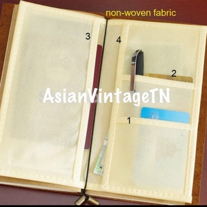 May include: A brown leather bound journal with a beige non-woven fabric interior. The fabric has four pockets, numbered 1 through 4, for holding cards, pens, or other small items. The text "AsianVintageTN" is printed on the fabric.