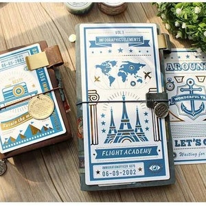 May include: Three vintage-style travel journals with blue and gold accents. The covers feature illustrations of a world map, the Eiffel Tower, and an anchor. The journals have the text "06-09-2002", "VOL 1 INFOGRAPHICSELEMENTS", "AROUND WONDERFUL TRIP", "FLIGHT ACADEMY", "LET'S GO Waiting for you", and "Retain the memories 1956 IMMIGRATIONOFFICER 679" printed on them.