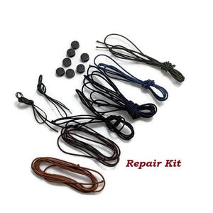 May include: A repair kit for shoes or bags includes multiple lengths of elastic cord in brown, black, and blue, along with black plastic buttons. The text "Repair Kit" is printed in red.