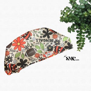 May include: A patterned surgical cap featuring a football and floral design in orange, black, and cream colors. The word "BENGALS" is printed on the cap. The cap also has the "SMC CAPS" logo.