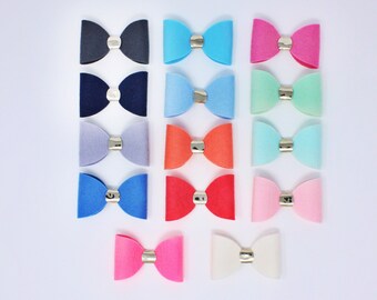 May include: A set of 15 felt hair bows in various colors, including blue, pink, green, red, and white. Each bow has a silver metal center.