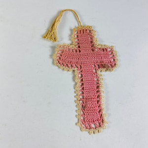 May include: A pink crocheted cross bookmark with a gold tassel.