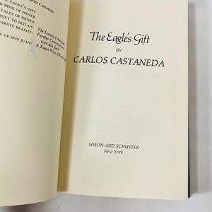 Op de afbeelding: Een open boek met de titel "The Eagle's Gift" van Carlos Castaneda. Het boek heeft cr&egrave;mekleurige pagina's met zwarte tekst. De naam van de uitgever, Simon and Schuster, en New York staan onderaan de pagina.