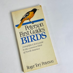 May include: A yellow and black bird perched on a branch, with the text "Peterson First Guides BIRDS A simplified field guide to the common birds of North America Roger Tory Peterson" on the cover of a book.