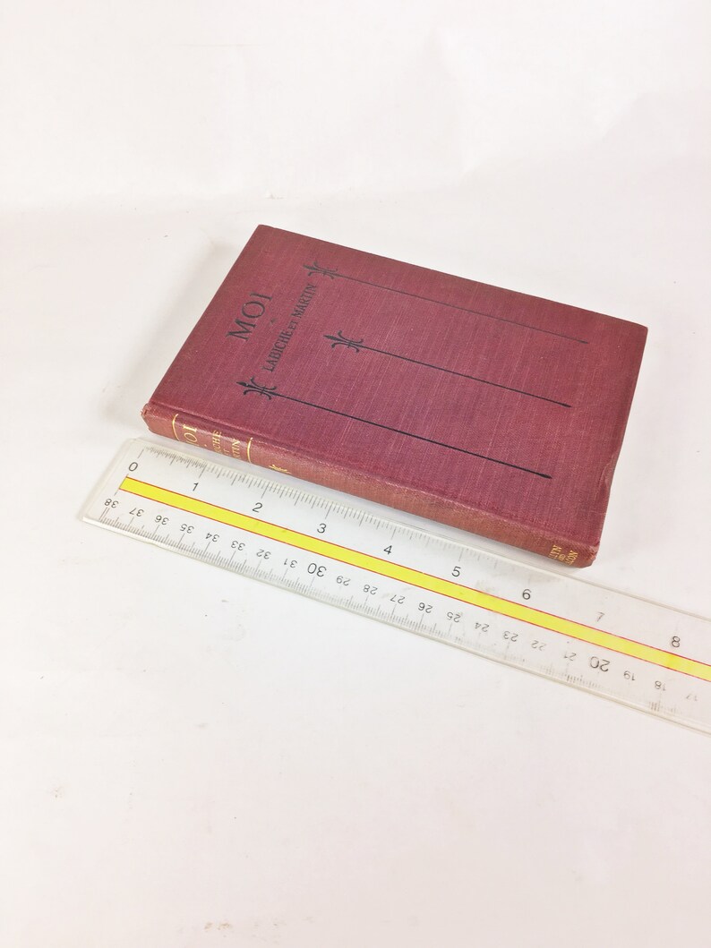 May include: A burgundy hardback book with the title "MOI" and the text "LABICHE ET MARTIN" on the spine. The book is lying on a white surface with a ruler next to it.