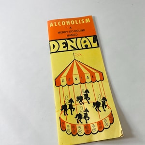 May include: A vertical pamphlet with a yellow background featuring an orange header that reads ALCOHOLISM A MERRY-GO-ROUND NAMED DENIAL in black text. Below, a graphic shows a carousel with orange and white stripes and black horse figures.