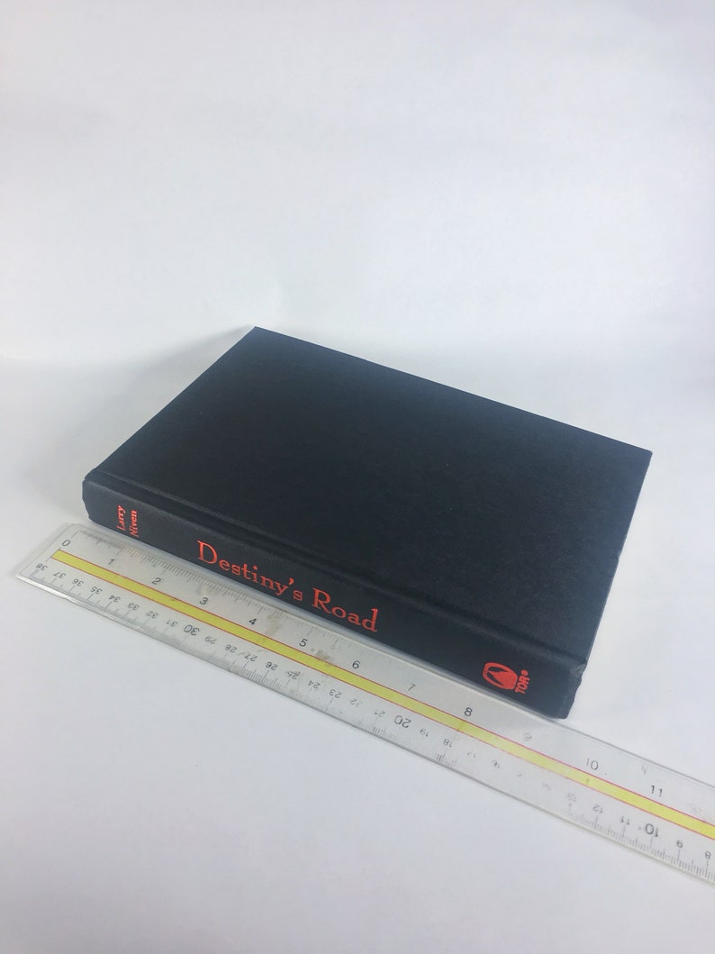 May include: A black hardcover book with the title "Destiny's Road" in red lettering on the spine. The book is lying on a white surface.