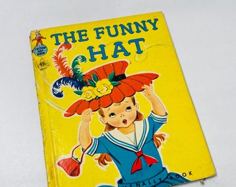 May include: A vintage children's book titled "The Funny Hat" with a yellow cover and a colorful illustration of a girl wearing a large red hat with feathers and flowers. The book is published by Rand McNally.