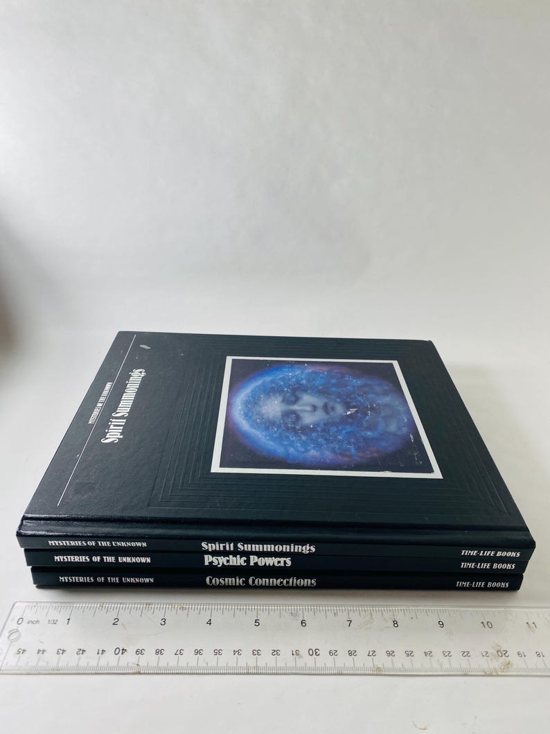 May include: A stack of black books titled "Spirit Summonings," "Psychic Powers," and "Cosmic Connections." The top book features a blue and white image of a face. The books are part of the "Mysteries of the Unknown" series.