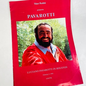 May include: A red and white concert program for a Luciano Pavarotti performance in Houston, Texas on February 2, 1994. The program features a photo of Pavarotti smiling and wearing a red jacket. The text "Tibor Rudas presents PAVAROTTI" is at the top of the program.