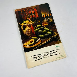 May include: A vintage brochure for "The Avocado Bravo" with a photo of avocados, lemons, and a ceramic pitcher. The brochure is on a wooden surface and has a green "Produce" tag.