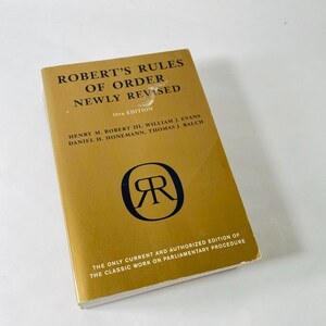May include: A gold-colored book titled "Robert's Rules of Order Newly Revised" with black text. The book's cover features the text "10th Edition" and the names of the authors. A black logo with the letters "R" is in the center. The bottom of the book reads "The only current and authorized edition of the classic work on parliamentary procedure."