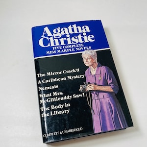 May include: A blue and black book cover with the title "Agatha Christie" and "Five Complete Miss Marple Novels". The cover features a portrait of Agatha Christie and the titles of five of her novels: "The Mirror Crack'd", "A Caribbean Mystery", "Nemesis", "What Mrs. McGillicuddy Saw!" and "The Body in the Library".