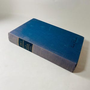 May include: A vintage hardcover book, "This I Remember" by Eleanor Roosevelt, with a blue cover and white lettering. The spine is a darker blue. A signature is visible on the top right corner. The book is a classic piece of literature.