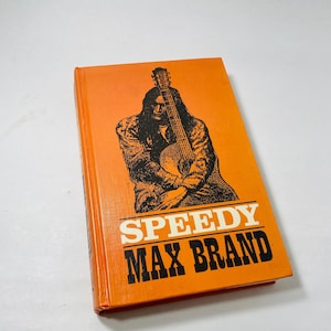 May include: An orange paperback book with a black and white illustration of a person holding a guitar. The title of the book is "Speedy Max Brand".