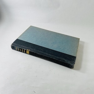 Könnte beinhalten: Ein Hardcover-Buch mit hellblauem Einband und schwarzem Rücken. Der Titel "Twelve Steps and Twelve Traditions" ist in goldener Schrift auf dem Rücken aufgedruckt. Das Buch ist rechteckig und scheint in gutem Zustand zu sein.