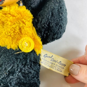 May include: Black and yellow plush toy with a button on the chest. The toy has a tag that reads "Gund Sani-Foam Foam Rubber Stuffed Surface Clean Only Do Not Immerse In Water".