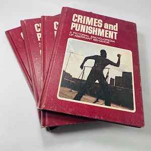 May include: A stack of five red hardback books with the title "Crimes and Punishment: A Pictorial Encyclopedia of Aberrant Behaviour" on the top book. The cover features a black silhouette of a person throwing a rock.
