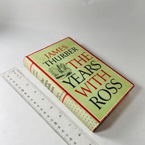 May include: A hardcover book titled "The Years With Ross" by James Thurber. The book has a light green cover with red and black text. A clear ruler is placed next to the book.