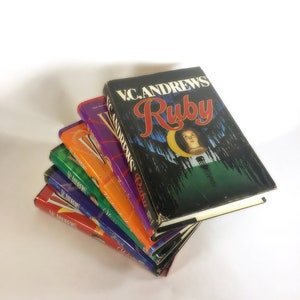 May include: A stack of six paperback books by V.C. Andrews. The top book is titled "Ruby" and features a woman with long dark hair and a white dress on the cover. The other books are titled "Dawn", "Secrets of the Morning", "Heaven", "Flowers in the Attic", and "My Sweet Audrina".