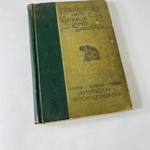 May include: An old book, "Living Creatures of Water, Land, and Air." The cover is green and gold, featuring an eagle illustration. Published by the American Book Company, with locations including New York, Cincinnati, and Chicago.