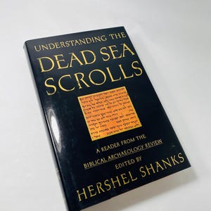 May include: A black book titled "Understanding the Dead Sea Scrolls: A Reader from the Biblical Archaeology Review" edited by Hershel Shanks. The cover features a fragment of a Dead Sea Scroll in Hebrew.